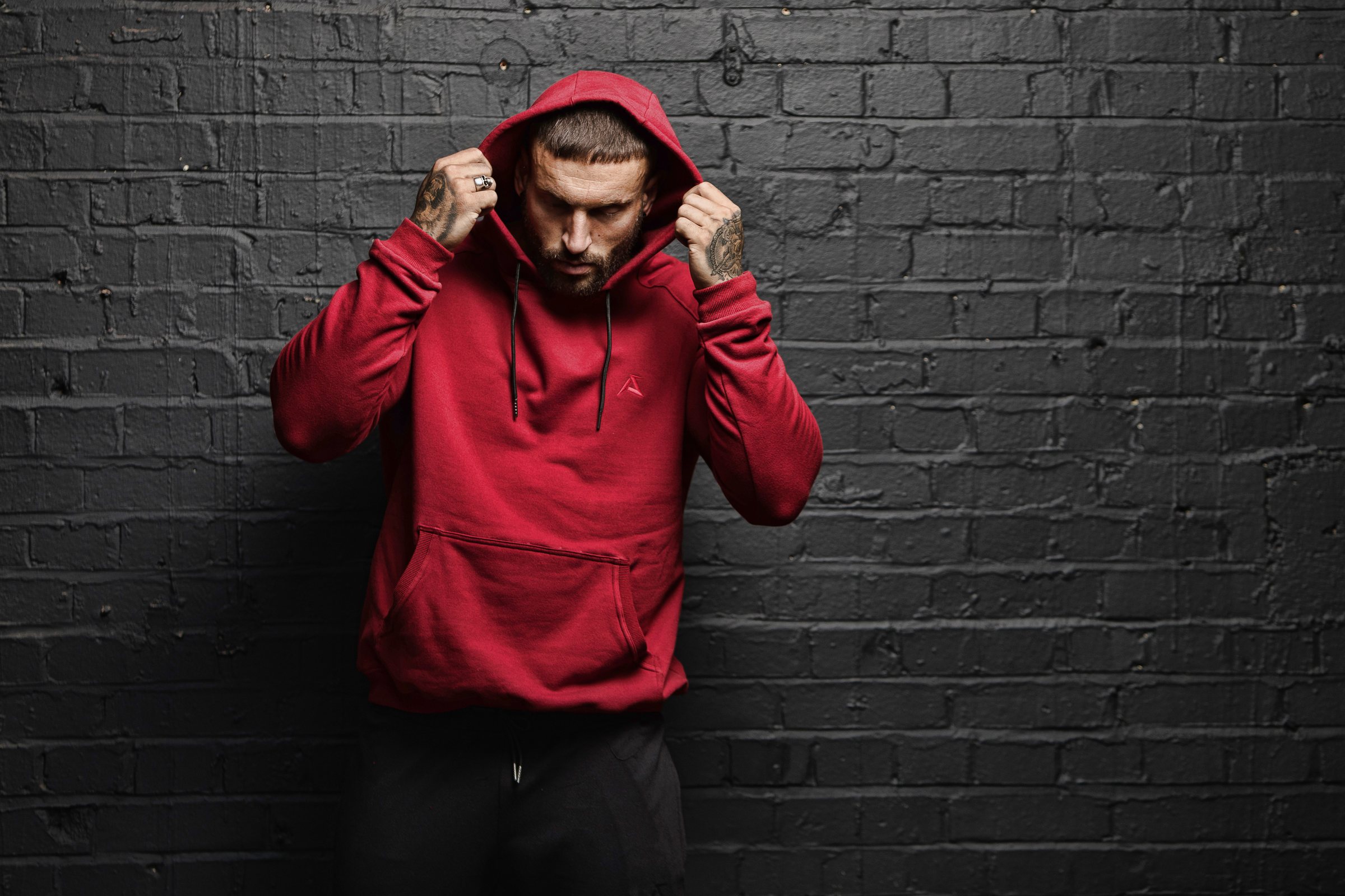 Alpha Skinz athlete in crimson Apex hoodie, hood up